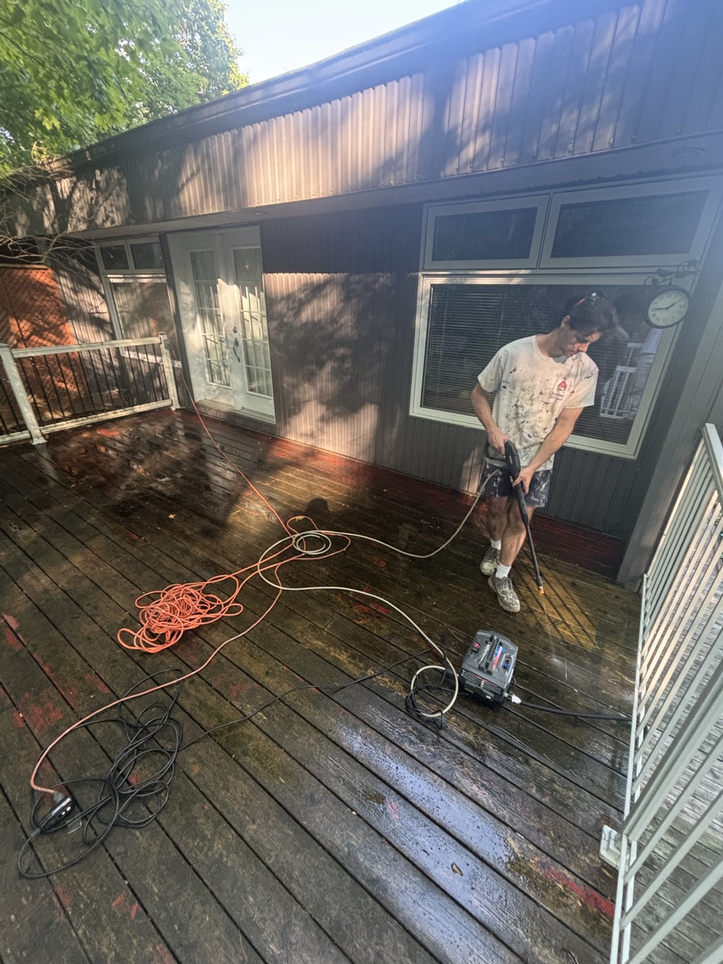 Un peintre de Peinture GT lave un patio de bois sous pression avant de le peindre